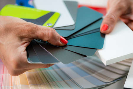 Woman looking at color palettes for interior decoration, compering matching colors
