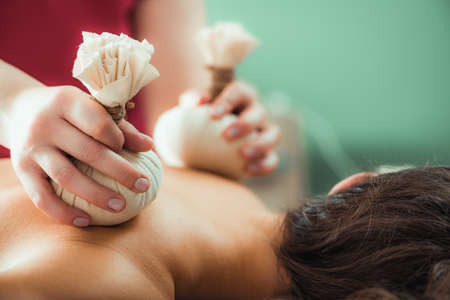 Kizhi massage or herbal bolus bags Ayurveda massage, hands of an Ayurveda Massage therapist pressing herbal bolus bags onto clientâs skinの写真素材