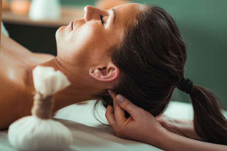 Kizhi or herbal bolus bags Ayurveda massage in a beauty salon, therapist pressing herbal bolus bags onto clientâs neck.の写真素材