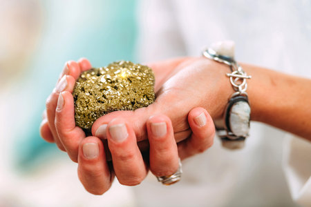 Abundance concept. Hands of a spiritual teacher, holding a natural shiny metal object of value,...