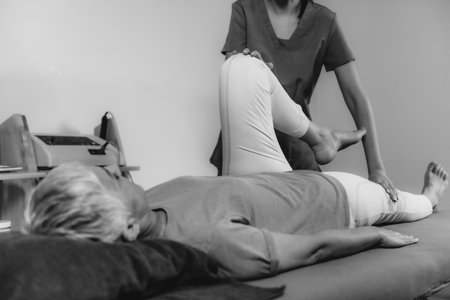 Physical Therapist Working with Leg. Senior Woman