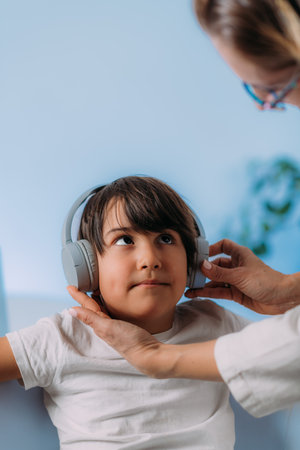 Pure tone audiometry test, checking childâs ability to hear different pitches and volumes of sound. Boy Child with headphones listening sounds with different pitches and volumes, responding.の写真素材
