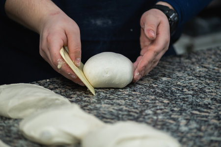 Chefs hand preparing round pieces of dough for pizza in restaurant kitchenの写真素材