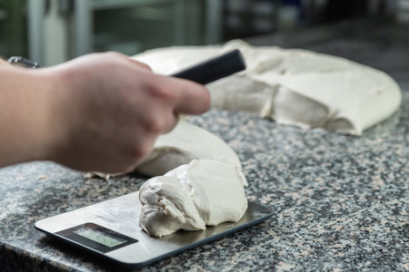 Weighing dough on a scale in large restaurantの写真素材