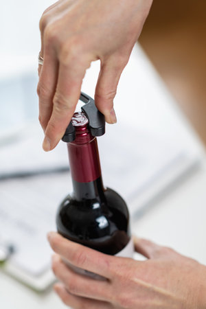 Wine tasting experience. The sommelier removes the foil covering the top of a wine bottle, while explaining the proper way to prepare a bottle of wine for service.の写真素材