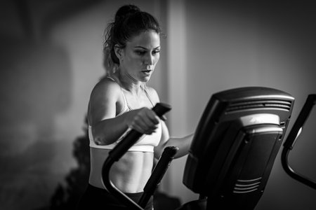 Woman exercising on cycling machine or exercise bike, black and whiteの写真素材