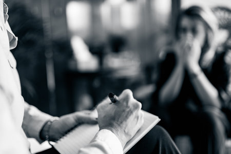 Psychotherapist taking notes during cognitive behavioral therapy session with patientの写真素材