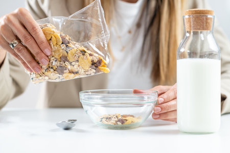 Healthy eating at work. Woman prepares a delicious bowl of nutritious muesli, the essence of a balanced lifestyle, showcasing the importance of wholesome ingredients and mindful food choices.の写真素材