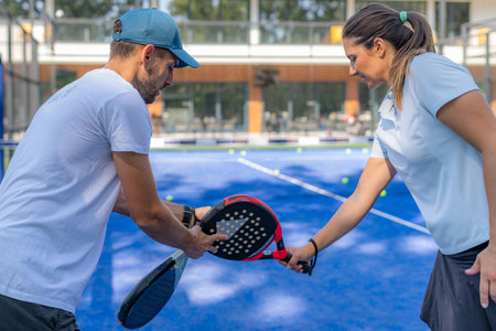 Padel training, a skilled coach teaches a woman the art of playing padel, fostering skill...