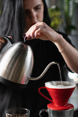 Female barista meticulously prepares drip coffee.