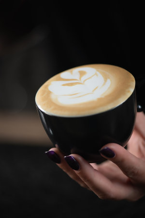 Hands of female barista holding a perfect cup of cappuccinoの写真素材