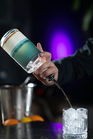 Bartender's hands pouring gin, crafting aromatics gin tonic cocktail