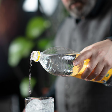 Bartender's hands pouring high quality tonic, preparing gin tonic cocktail.の写真素材