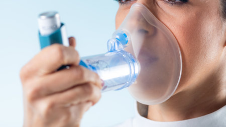 Woman manages her asthma with an inhaler featuring an extension tube for enhanced accessibility