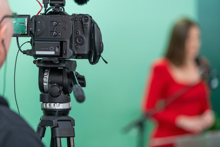 Cameraman in a studio recording an unrecognizable media person on the green backgroundの写真素材