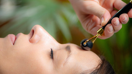Relaxing benefits of Guasha face massage with a jade stone roller, promoting skin rejuvenation and wellnessの写真素材