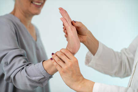 A medical professional conducts a comprehensive Carpal Tunnel Syndrome test with a senior woman, assessing wrist function and nerve healthの写真素材