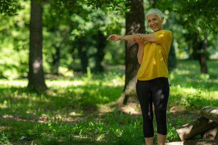 Active senior woman stretching outdoors after workout session.の写真素材
