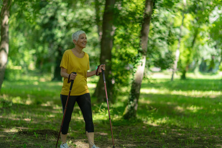 Senior woman enjoys nordic walking exercise amidst natures beauty.の写真素材