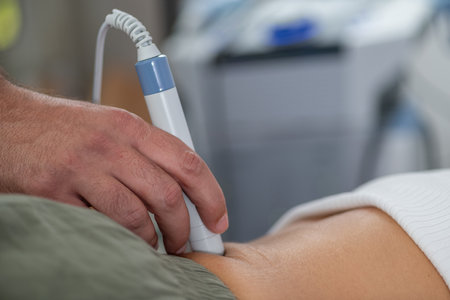 Physical therapist uses laser therapy on a patients lower back to alleviate pain, reduce...