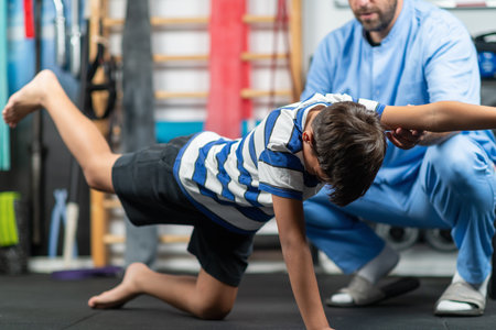 Physical therapist instructing a young boy in exercises, focusing on improving mobility, strength, and balance during a personalized rehabilitation sessionの写真素材