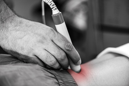 Physical therapist uses laser therapy on a patients lower back to alleviate pain, reduce inflammation, and promote tissue healing, enhancing mobility and recoveryの写真素材