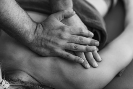 Physical therapist performs a deep tissue massage on a patients shoulder to relieve muscle tension and improve mobility in a therapeutic settingの写真素材