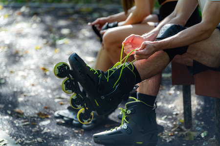 Couple prepares for an outdoor rollerblading adventure, putting on their rollerblades together in a scenic park. This moment captures their anticipation and teamwork before enjoying the activityの写真素材