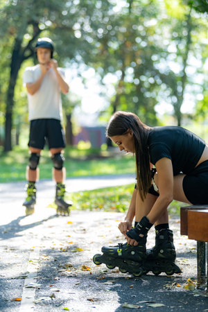Couple prepares for an outdoor rollerblading adventure, putting on their rollerblades together in a scenic park. This moment captures their anticipation and teamwork before enjoying the activityの写真素材