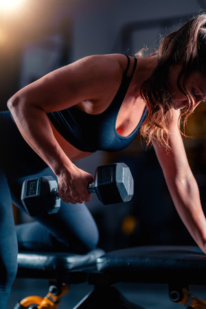 Woman doing training for back with dumbbells, lifting weights to build strengthの写真素材