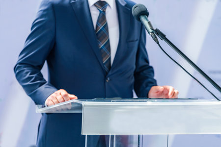 Male politician at press conference shares critical updates, informing media. His confident delivery promotes clear journalism and enhances public understanding of key issues.の写真素材