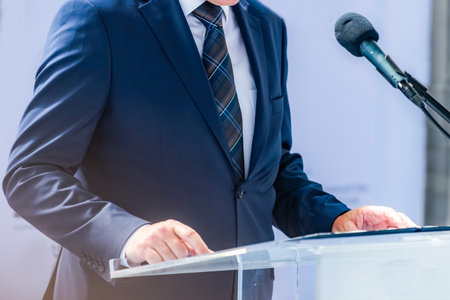 Politician speaker at press conference shares critical updates, informing media. His confident delivery promotes clear journalismの写真素材