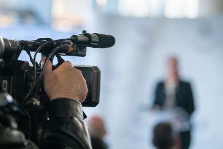 TV camera focused on podium during press briefing. Highlights communication accuracy, media presence, and organized public message delivery.の写真素材
