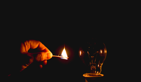 Fire match and incandescent light on black backgroundの写真素材