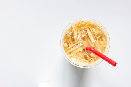 Top view of glass of iced coffee on white background and red strawの写真素材