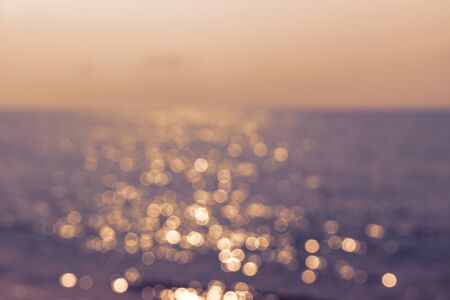 Blur sunset with bokeh sun light and wave on the seaの写真素材