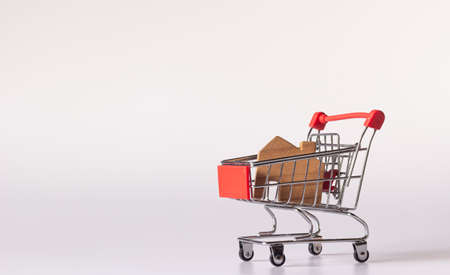 Small wooden house in small shopping cart on white background and copy spaceの写真素材