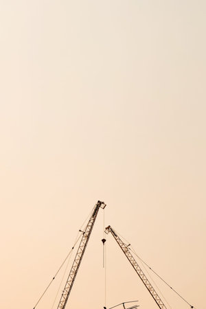A tall construction crane and an orange sky background.の写真素材