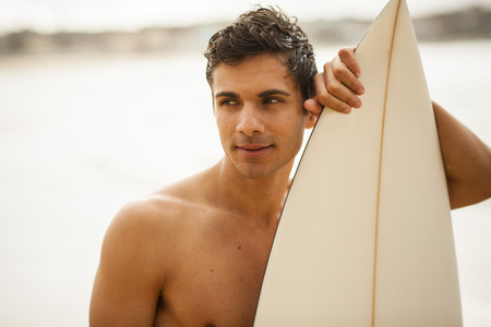 Portriat of a young, Italian surfer holding his surfboardの写真素材