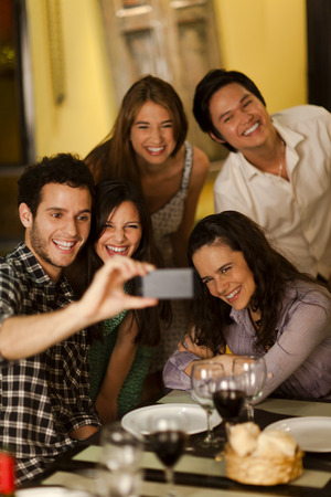 Group of young adults taking a selfie photo in a restaurantの写真素材