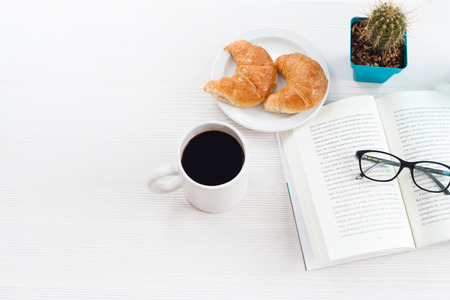 Top view business office.Book, coffee and croissant on white table.