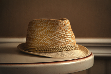 The window light is shining on the straw hat on the tableの写真素材