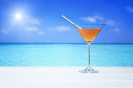 closeup cocktail drink on wooden table with sea viewの写真素材
