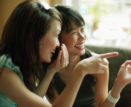 Young women whispering and pointing.の写真素材