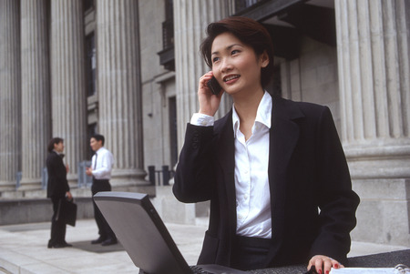 Female executive with laptop computer and cellular phoneの写真素材