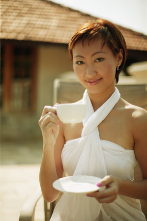 Young woman holding cup and saucer, looking at cameraの写真素材