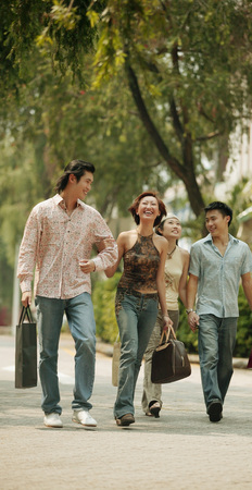 Couples walking hand in hand, carrying shopping bagsの写真素材
