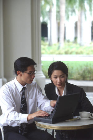 Male and female executives working on laptop computer in cafeの写真素材