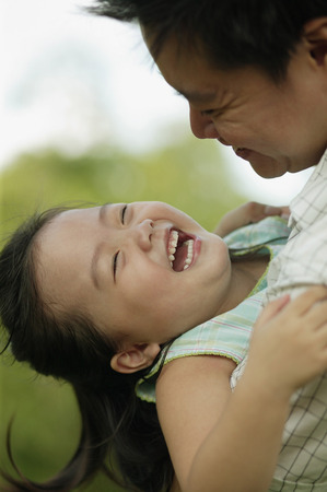 Father carrying young daughter, looking downの写真素材