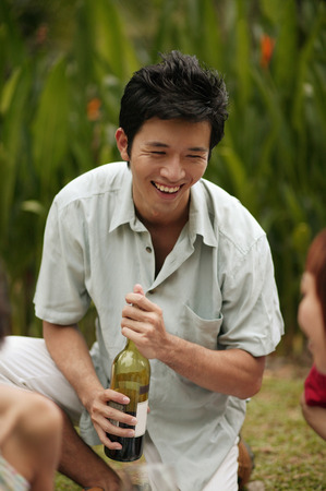 Young man holding bottle of wineの写真素材
